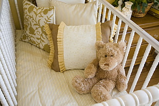 bear plush toy in crib beside pillows