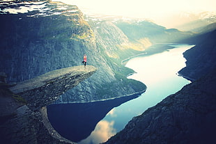 photography of person doing yoga pose near the cliff