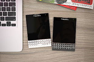 photo of two black Berry QWERTY phones on table
