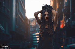 woman holding her hair up standing in front of high-rise buildings during daytime
