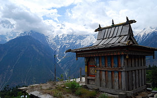 gray wooden temple near cliff and mountains