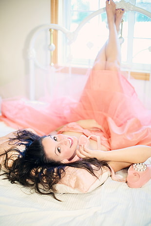 woman wearing pink dress lying down on white mattress