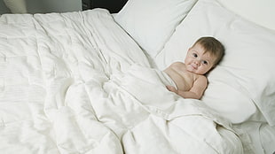 topless toddler lying on bed