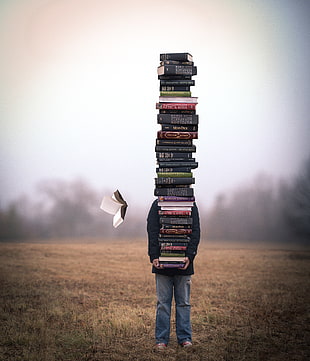 person standing carrying assorted books during daytime HD wallpaper