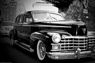 grayscale photography of classic car on road beside street sign