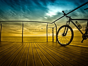 gray and whtie hardtail mountain bike near metal railing during golden hour, barcelona