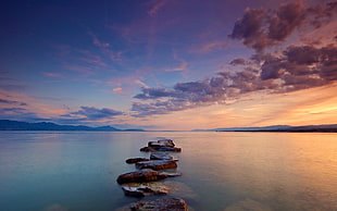 stones on body of water during sunset