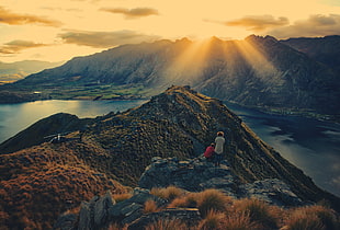 two person on mountain alp near body of water during golden hour, lake wakatipu