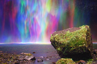 photography of stone near waterfalls rainbow
