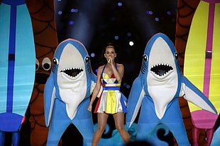 woman holding microphone near two shark mascots
