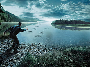 man tossing stone pm river during daytime HD wallpaper