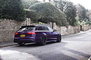 purple 5-door hatchback near gray brick wall