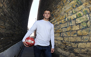 man holding soccer ball near wall