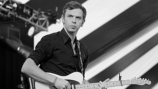 grayscale photography of man playing guitar