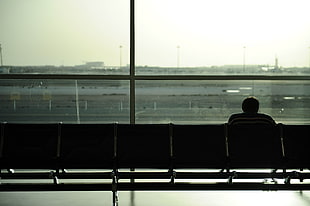 silhouette photo of sitting person on airport waiting area