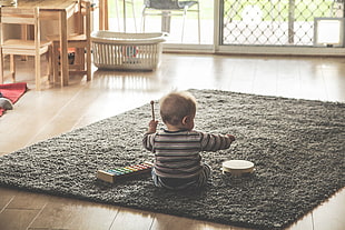 baby boy playing xylophone on grey rug