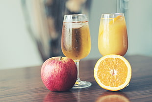 red apple and sliced lemon fruit beside two wine glasses