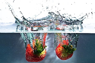 two strawberries drop on water