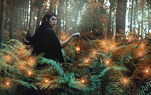 woman holding candle lantern inside forest