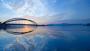 mirror photography of bridge and body of water during golden hour