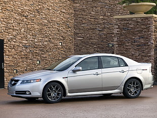 silver Acura TL parked near brown brick wall