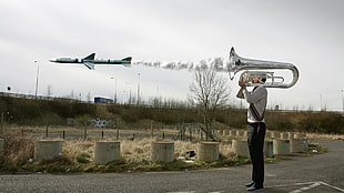 man standing holding firing a missile using tuba during daytime