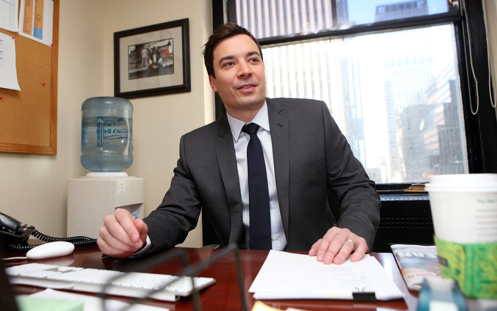 man wearing black suit jacket sitting inside room near window