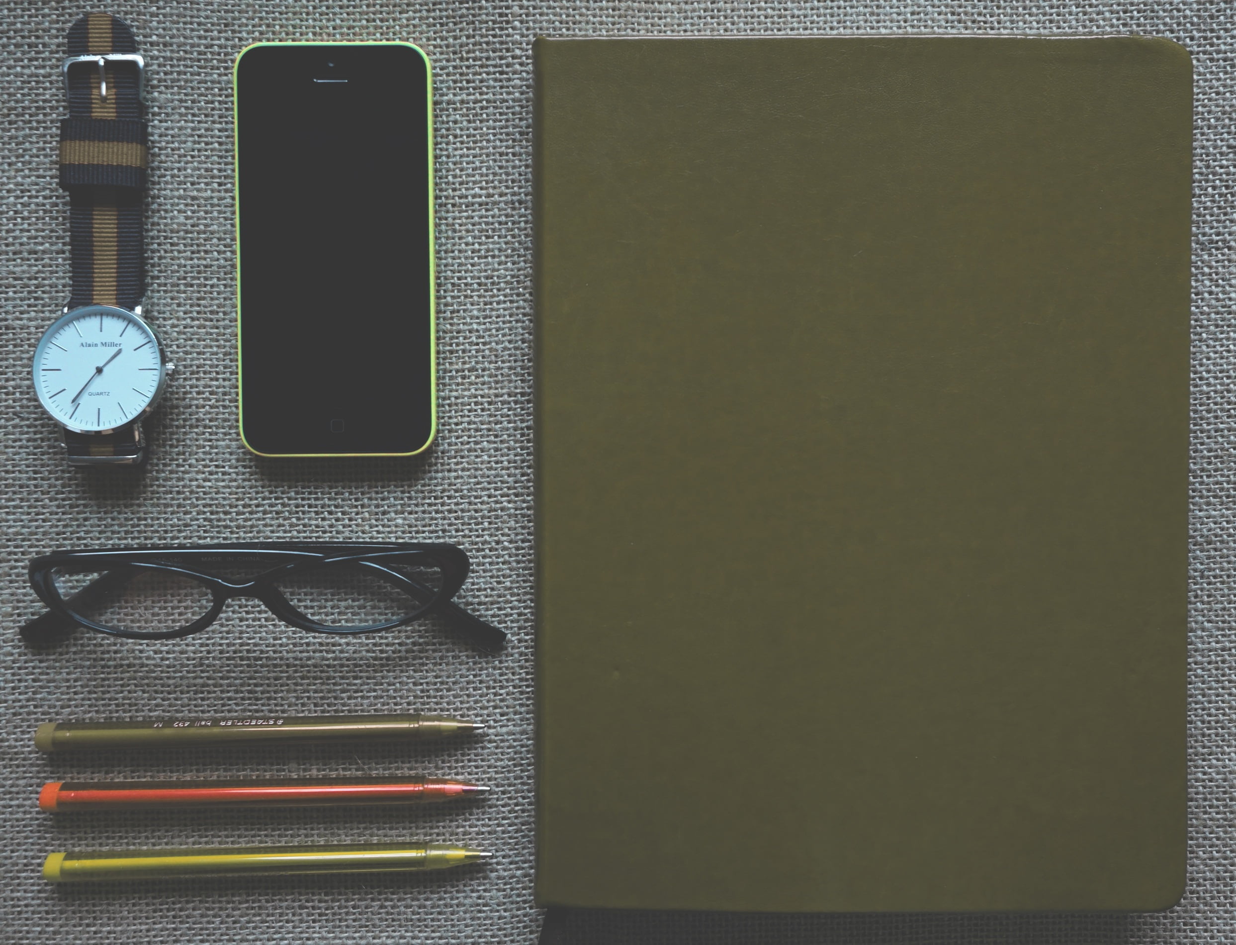 green iPhone 5c and eyeglasses with black frame near round silver framed analog watch with brown and black strap