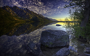 calm lake surrounded with brown rock formations at golden hour