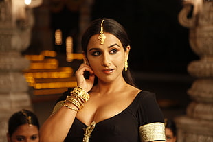 woman in black plunging top wears gold-colored bangles