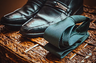 polka-dotted necktie beside pair of black leather buckle shoes