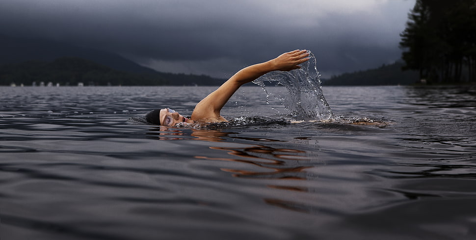 man swimming in sea during daytime HD wallpaper