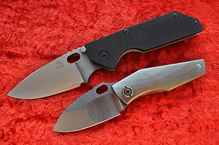 two gray and black knives on red cloth