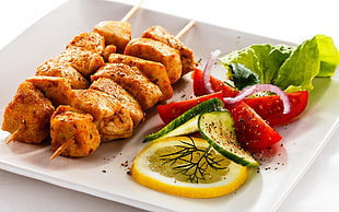grilled food with sliced lemon, lettuce, cucumber and tomato sidings