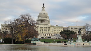 white capitol near body of water under cloudy sky