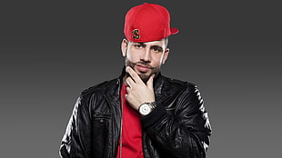 man wearing black leather zip-up jacket and red top with red fitted cap