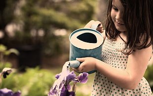 girl watering purple petal flowers using watering can