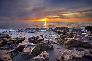 solid rocks near seashore during sunset