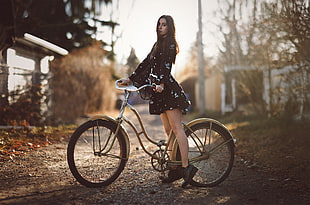 woman riding on brown beach cruiser bike standing on brown road taken during daytime