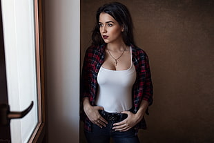 woman wearing white camisole and red plaid shirt with hands on jeans