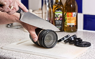 man cutting telephoto lens on top of white cutting board