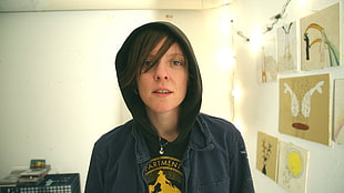 photo of man wearing blue hoodie jacket standing inside room