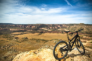 black full-suspension bicycle on brown rocky surface during daytim