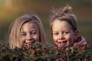 boy and girl hiding on the bush during daytime HD wallpaper