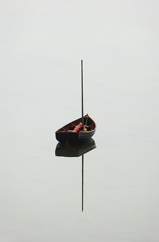 black canoe with reflection on body of water