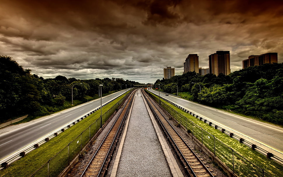 grey railway and concrete road near high-rise building HD wallpaper