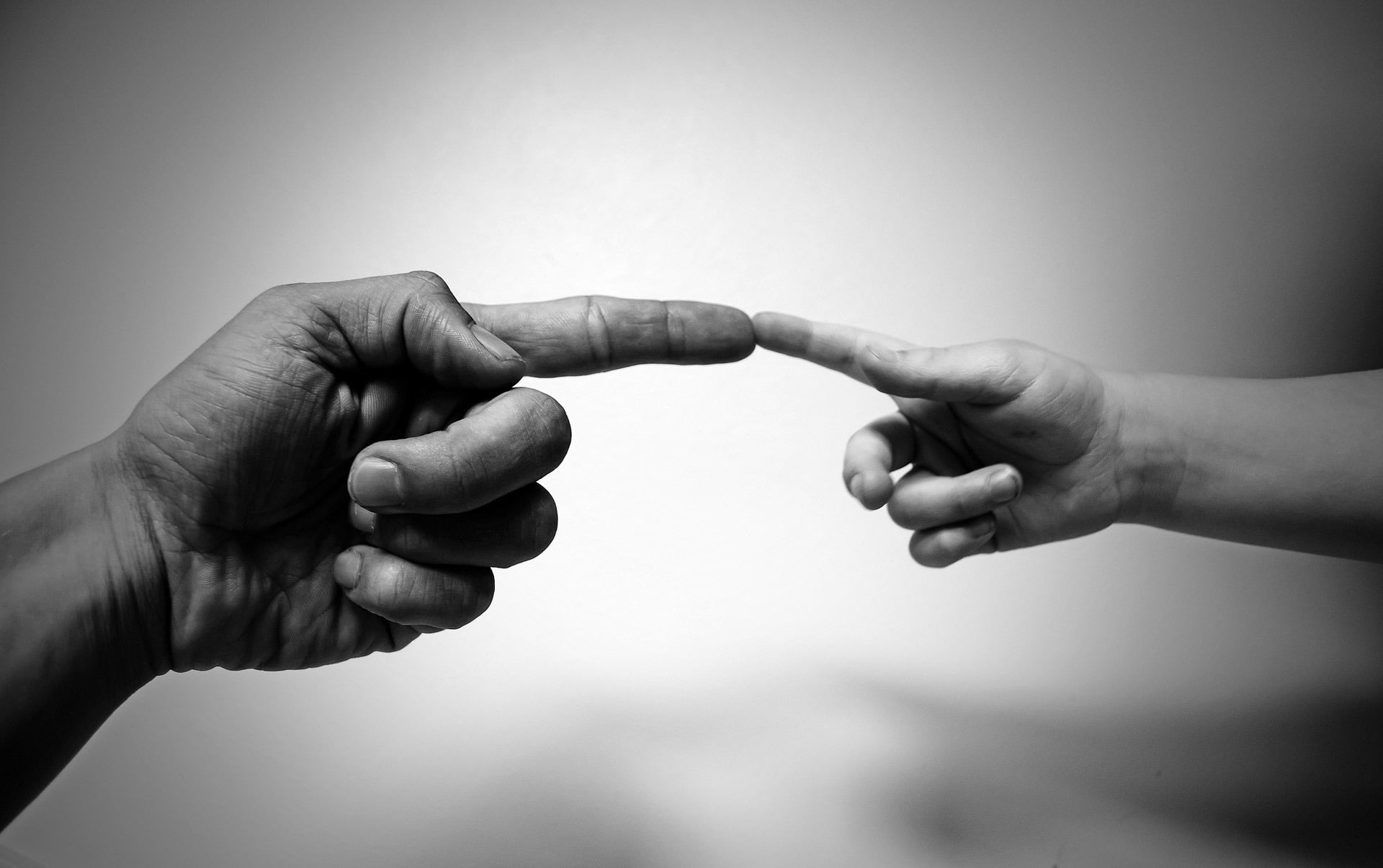grayscale photography of adult index finger and toddler's index finger