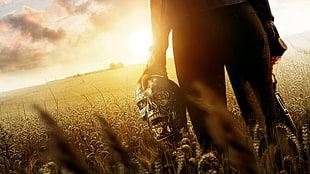 person holding Terminator head on wheat field