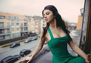 woman wearing green sleeveless dress beside window