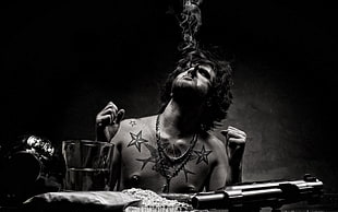 grayscale photo of man releasing a cigarette smoke on top